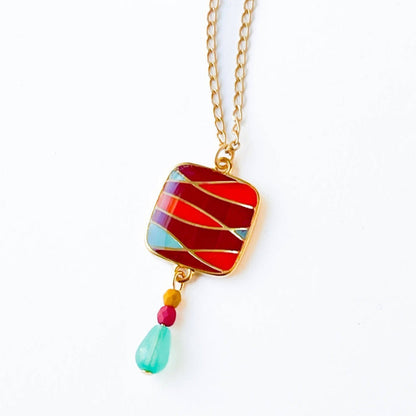 Nest Pretty Things | Mid-Century Pendant Necklace Assorted | Close up on the red/orange/blue striped pendant.